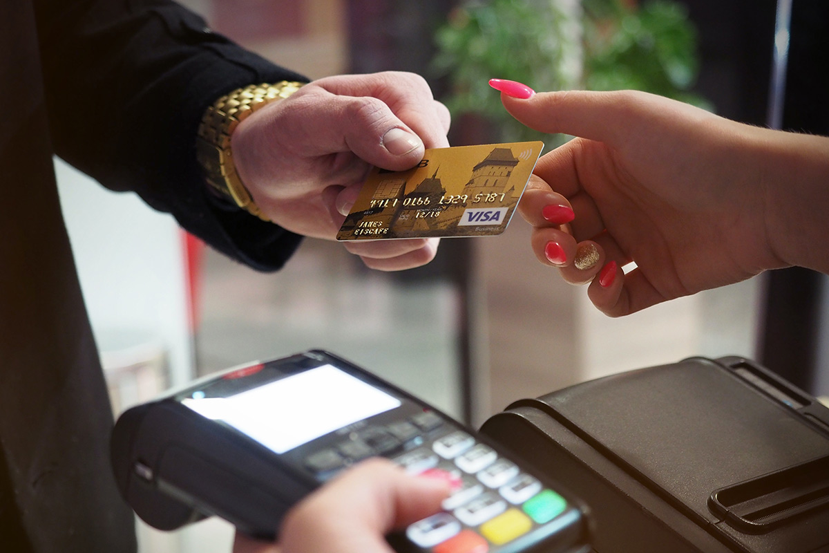 a person handing a debit card to a store clerk