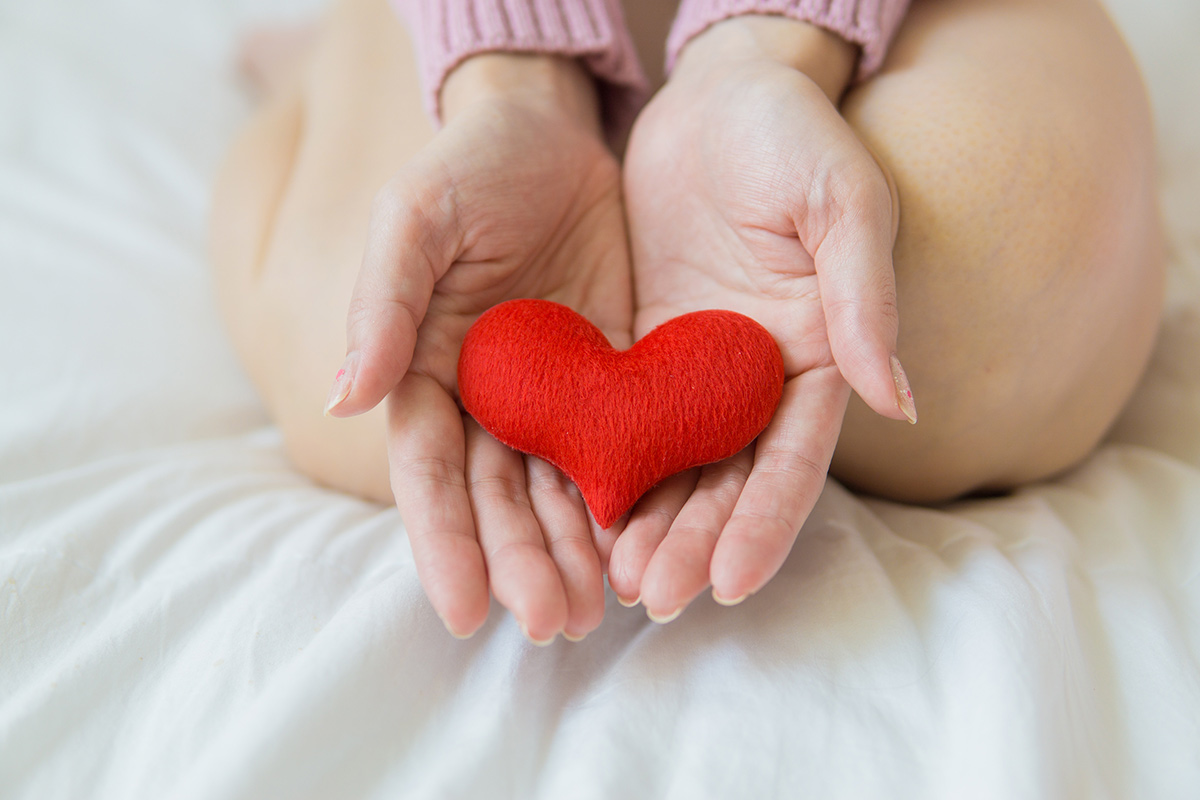 a person holding a small heart-shaped pillow