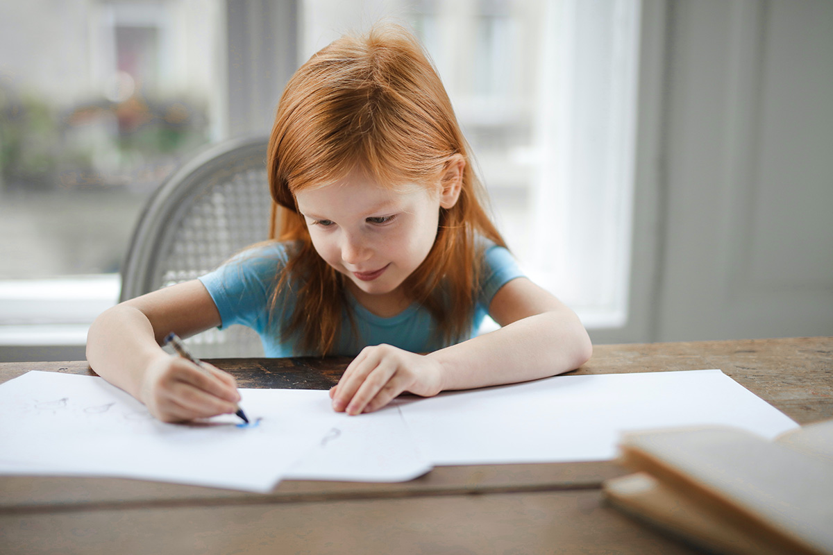 a girl coloring something on a sheet of paper at a table