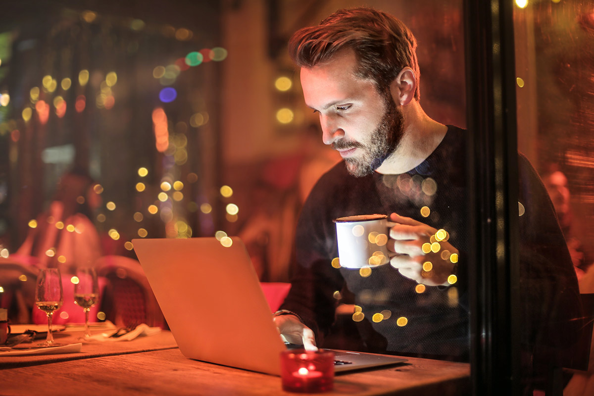 a man drinking coffee and looking at his e statement on a laptop computer