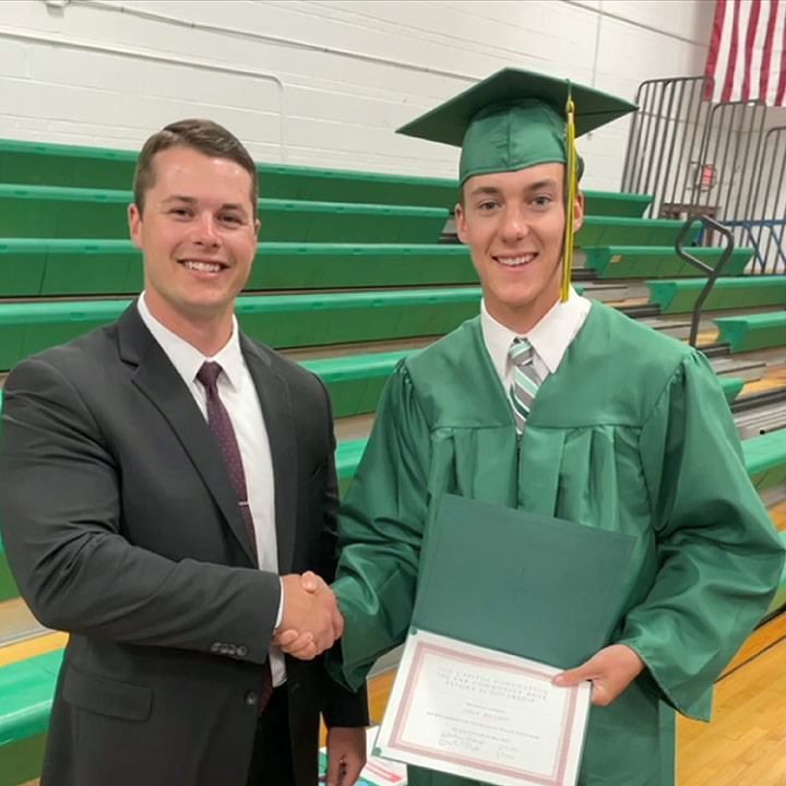 a member of The F N B Community Bank shaking hands with a high school graduate