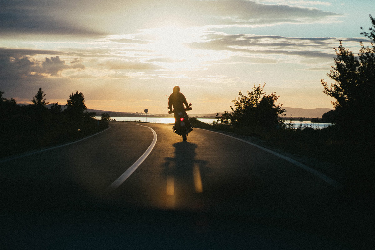a person riding a motorcycle on a curve in the road near water