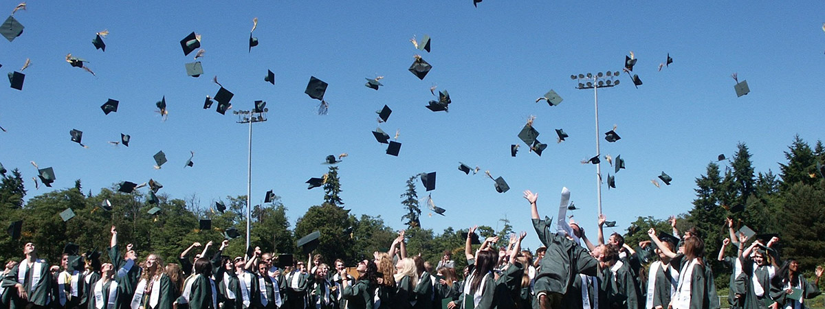 high school graduates tossing their caps into the air