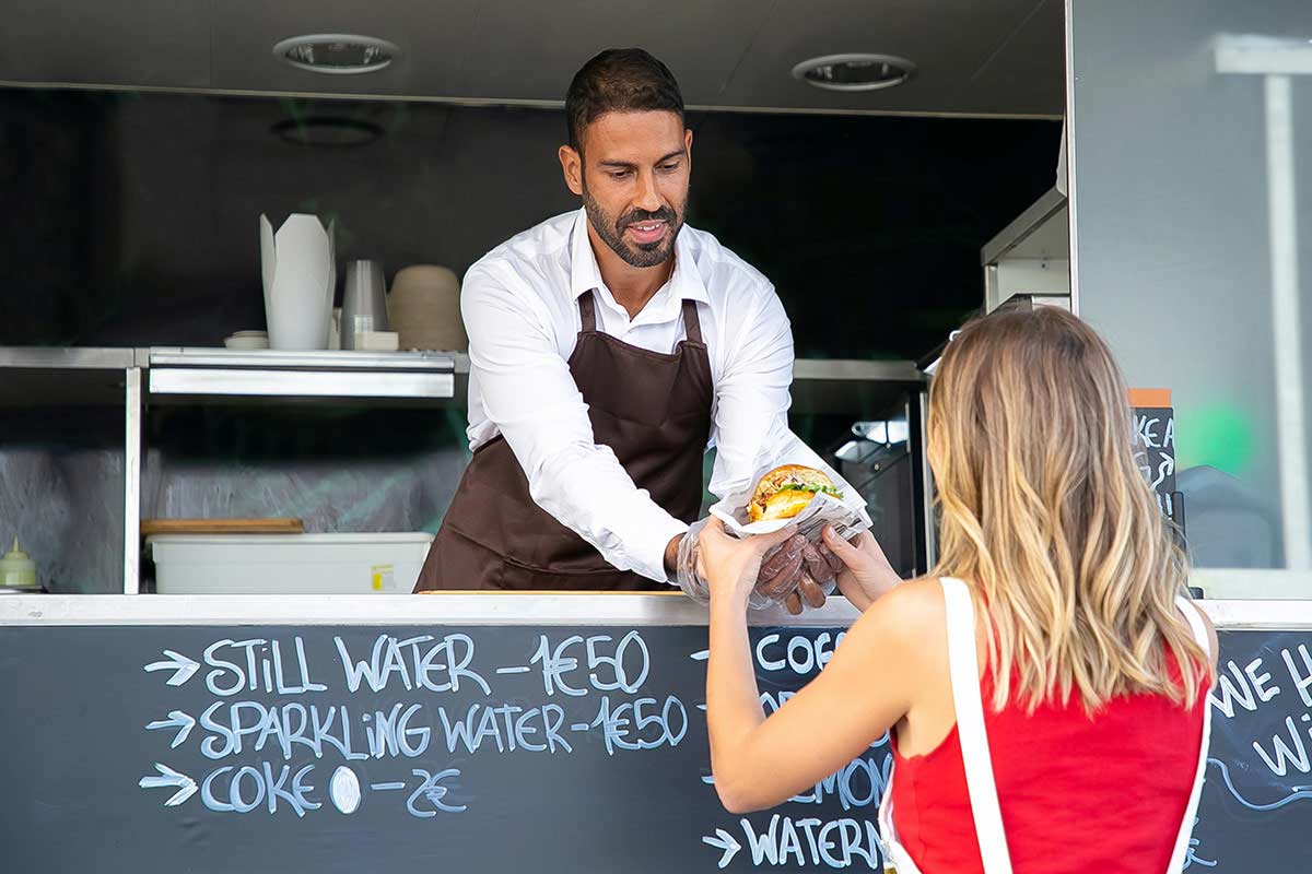 food vendor handing a sandwich to a customer