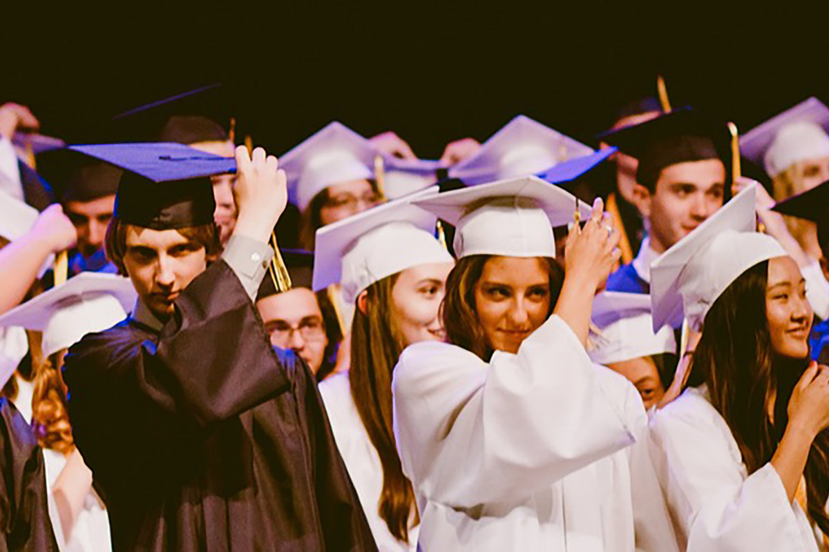 high school graduates moving their tassels from one side of the cap to the other