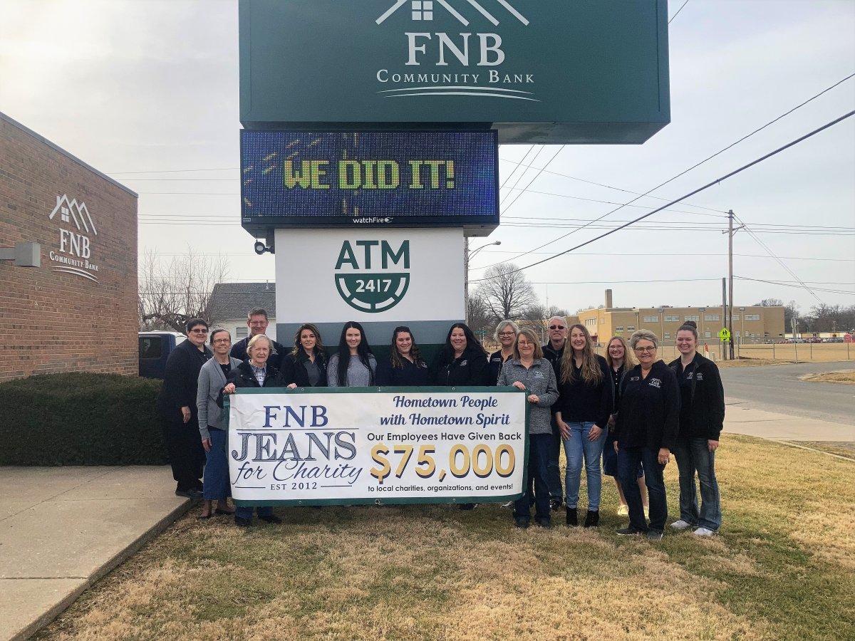 employees of F N B Community Bank standing behind a sign showing a donation to Jeans for Charity